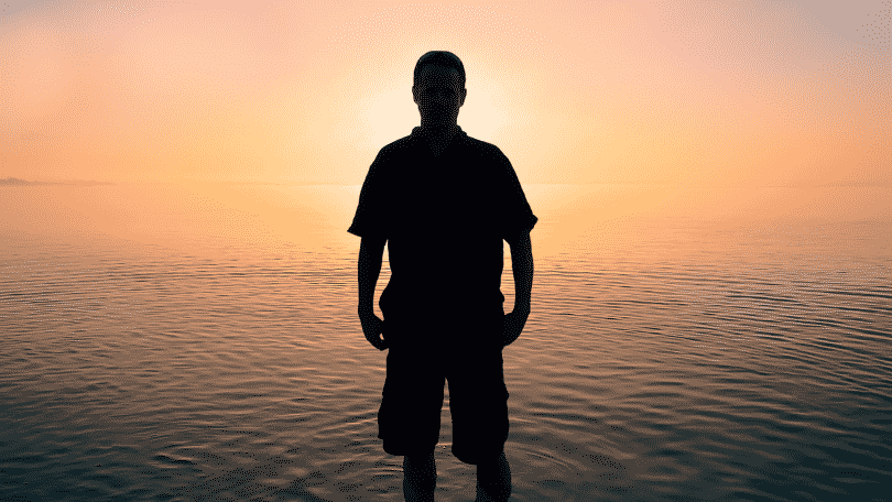 Silhueta de homem na praia observando o por do sol