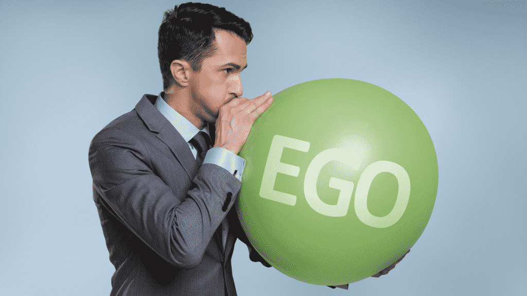 Homem enchendo balão com a palavra "ego" escrita