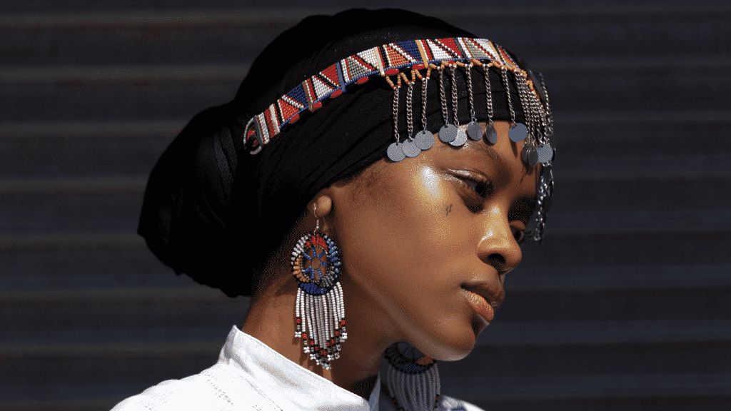 Mulher usando turbante e acessórios coloridos, em foto de perfil