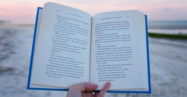 Pessoa segurando livro aberto em beira de praia