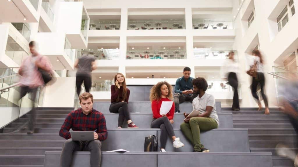 Estudantes sentados em escadaria de faculdade