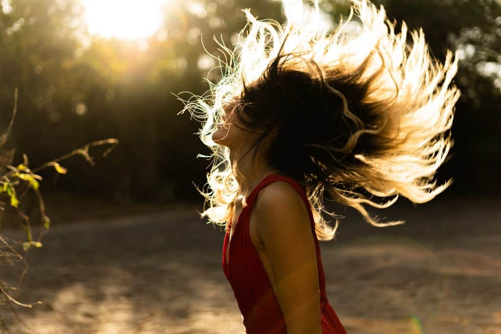 Mulher branca balançando o cabelo.