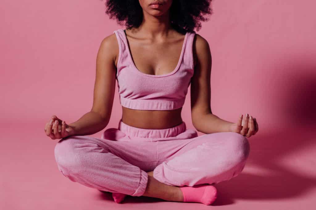 Mulher de roupa rosa meditando em um espaço da cor rosa