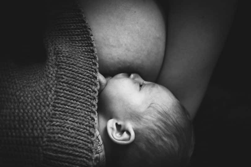 Imagem em preto e branco de um bebê sendo amamentado pela mãe