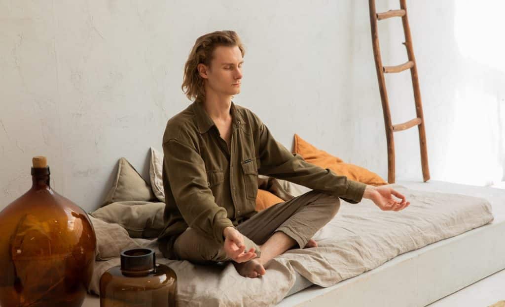 Homem em prática meditativa em ambiente interno.