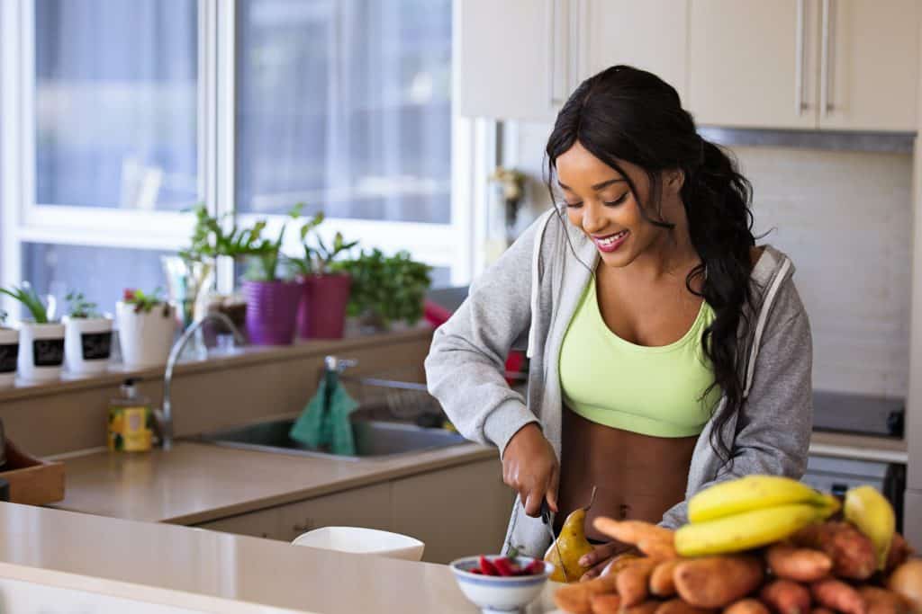 Mulher em sua cozinha cortando frutas