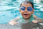 Criança em uma piscina com óculos de proteção