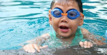 Criança em uma piscina com óculos de proteção