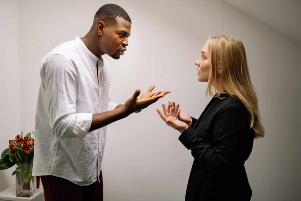 Um homem apontando o dedo na cara de uma mulher e brigando com ela