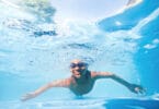 Menino nadando em piscina azul