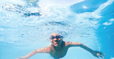 Menino nadando em piscina azul