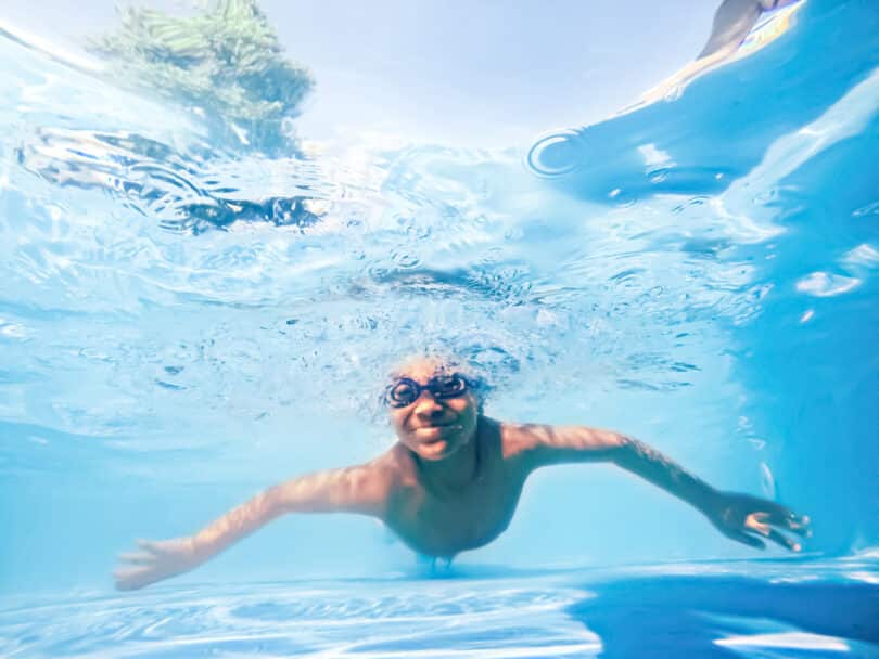 Menino nadando em piscina azul