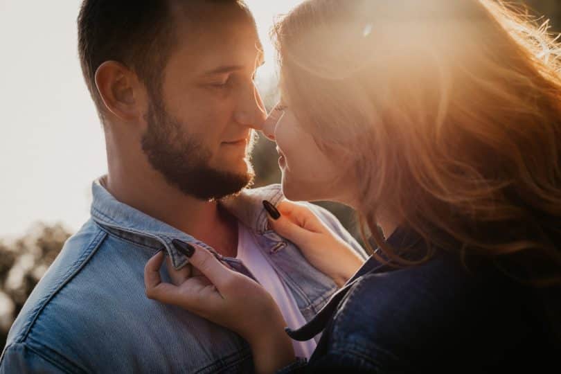 Homem e mulher brancos com os rostos próximos.