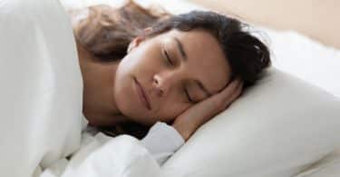 Mulher deitada numa cama dormindo.