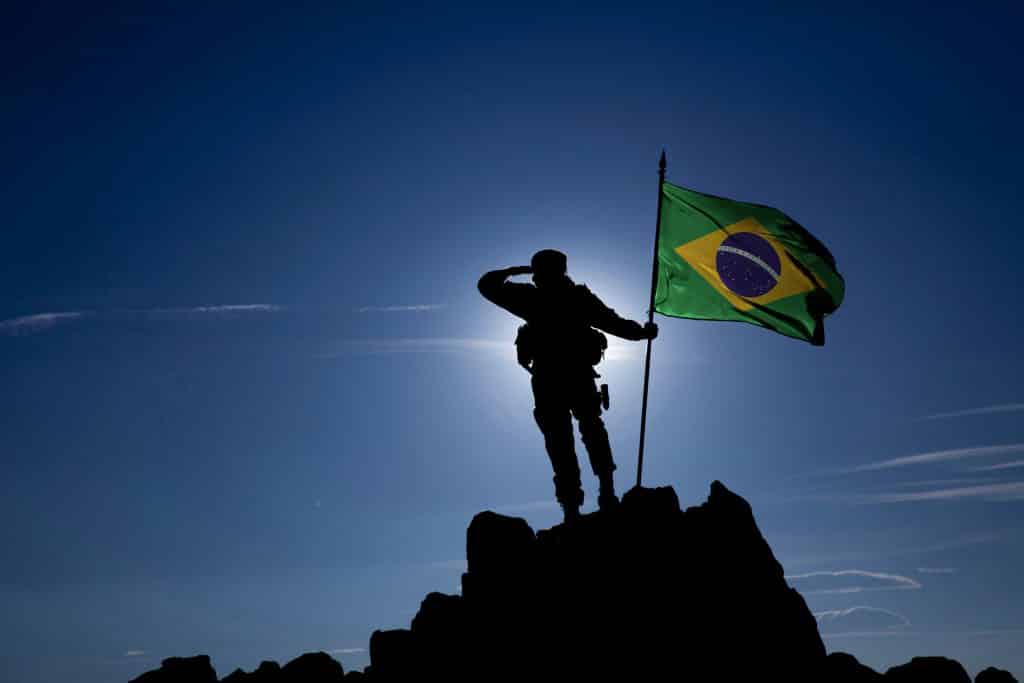 Soldado no alto da montanha com a bandeira brasileira