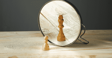 Peça de xadrez em frente ao espelho. Sua imagem refletida é bem maior