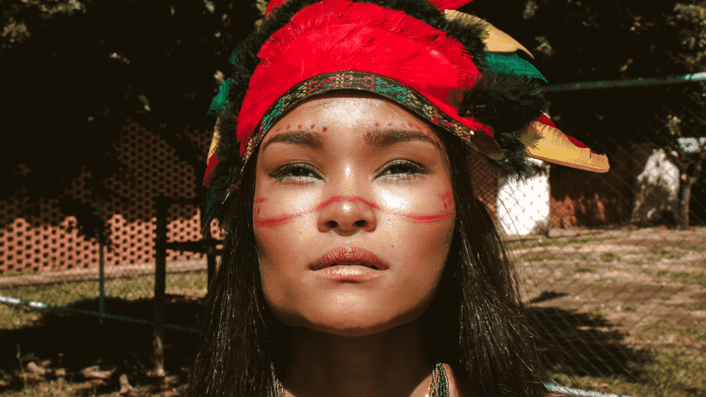 Mulher posando para a câmera usando vestes indígenas e pintura no rosto