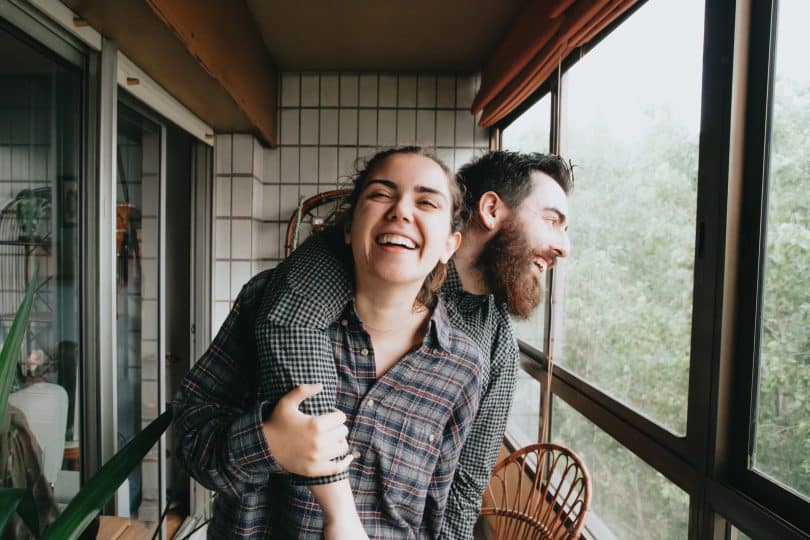 Homem e mulher brancos rindo abraçados.