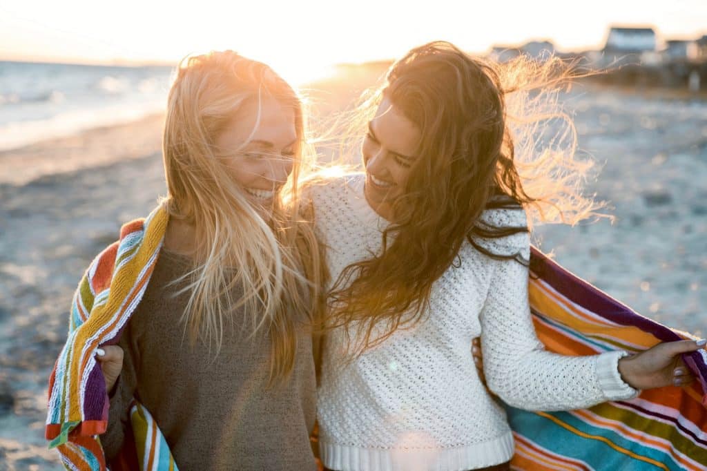 Mulher brancas juntas na praia com coberta em volta.