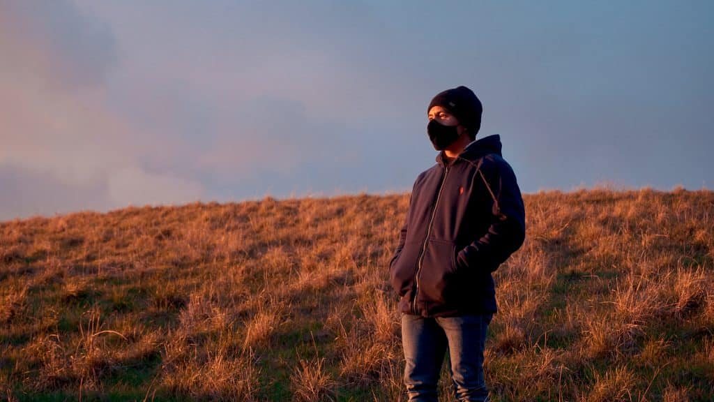 Homem branco com roupas de frio e máscara num campo.