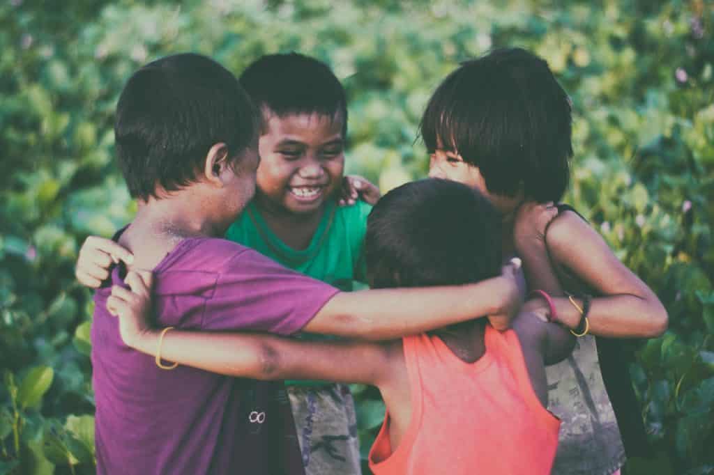 Crianças sorrindo e abraçadas brincando.