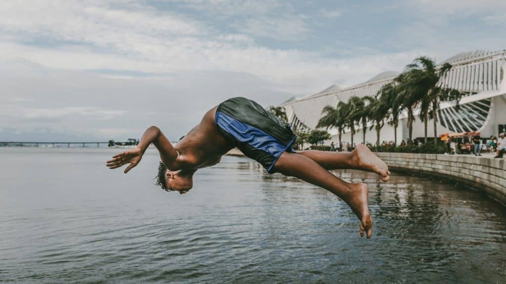 Menino está mergulhando no mar em frente ao Museu do Amanhã no Rio de Janeiro.