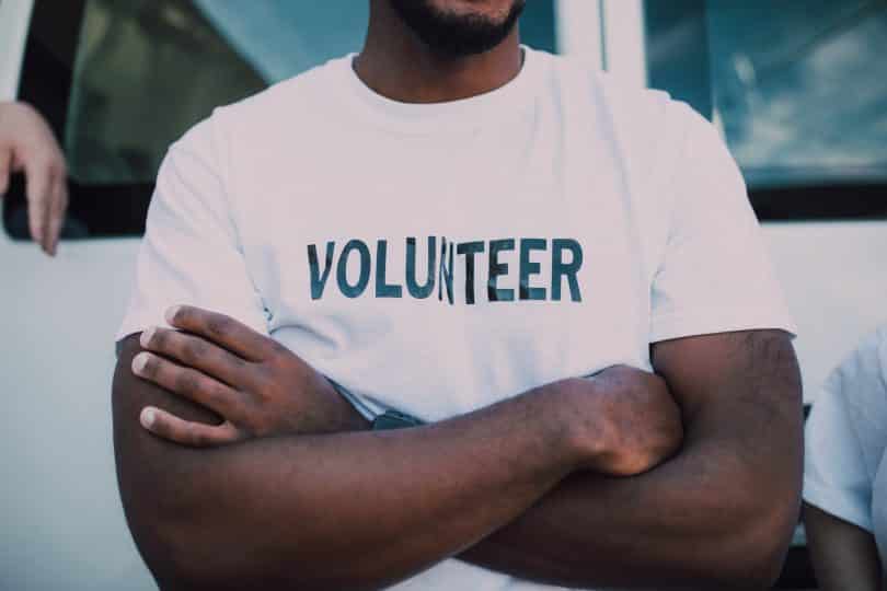 Homem negro usando camiseta escrito "volunteer".