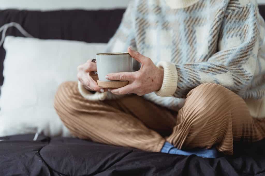 Mulher segurando xícara de café com as mãos.