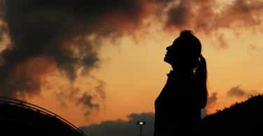 Silhueta de mulher durante o pôr do sol.