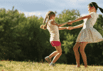 Duas meninas felizes dançando ciranda no parque