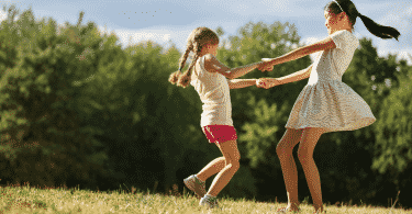Duas meninas felizes dançando ciranda no parque