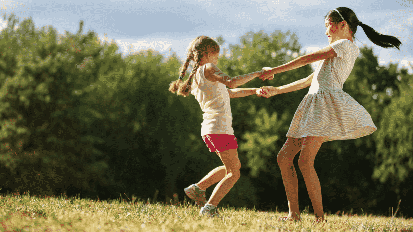 Duas meninas felizes dançando ciranda no parque