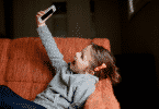 Criança deitada no sofá sorrindo tirando uma selfie