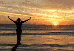 Silhueta de mulher com braços abertos observando o por do sol na praia