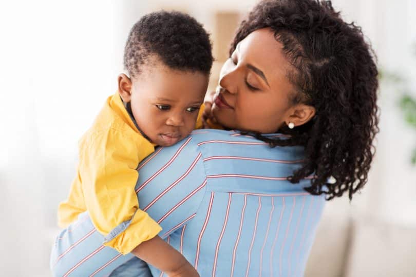 Mulher segura seu bebê no colo.