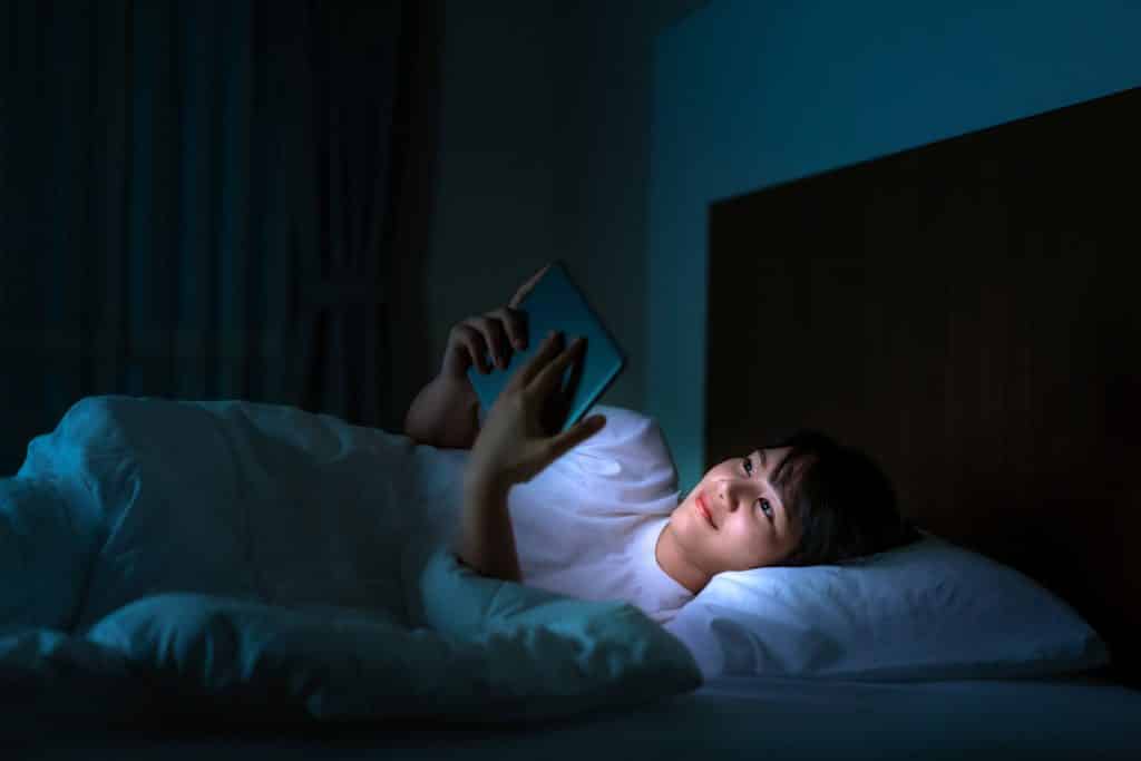 Mulher em celular assistindo a um vídeo antes de dormir