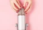 Mão de uma mulher com manicure perfeita perto do microfone está prestes a fazer batidas de unha. Fazendo sons ASMR. Gatilhos para relaxamento, boa noite de sono e alívio do estresse.