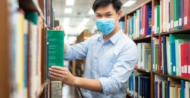 Homem asiático em uma biblioteca.