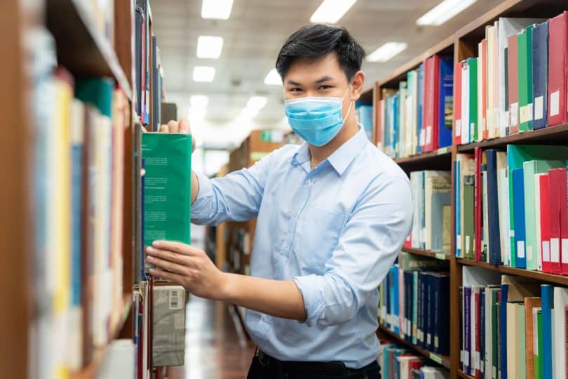 Homem asiático em uma biblioteca.