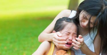 Mulher acalmando sua filha que está chorando.