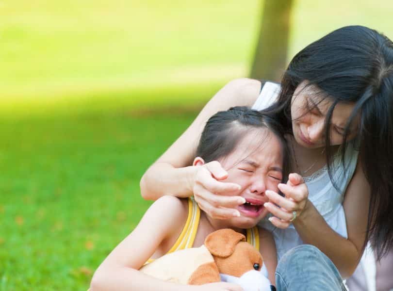 Mulher acalmando sua filha que está chorando.