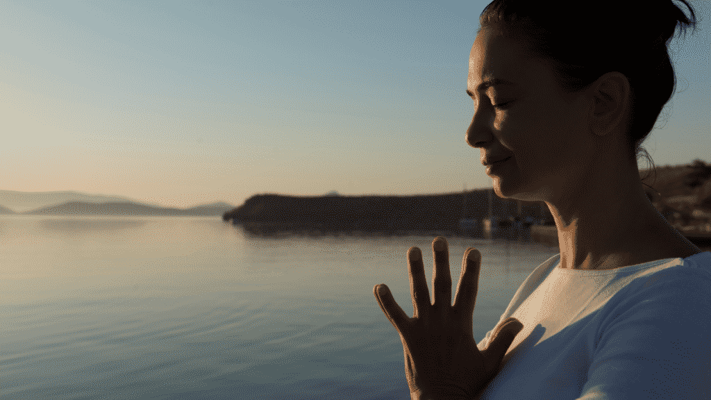 mulher de olhos fechados meditando na praia