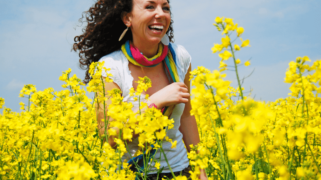 Mulher sorrindo passeando pelo campo de flores