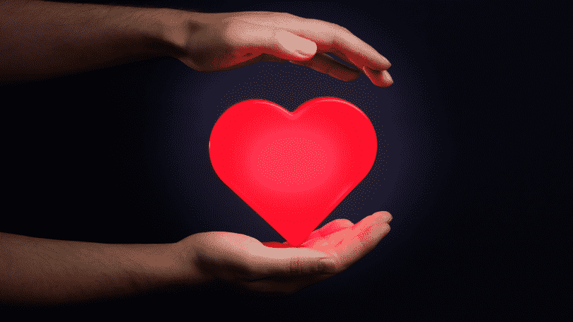 Coração vermelho entre as mãos de uma pessoa