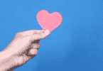 Imagem de uma mão segurando um coração de papel