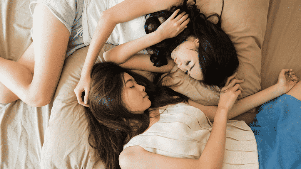 Duas mulheres deitadas em uma cama, dormindo