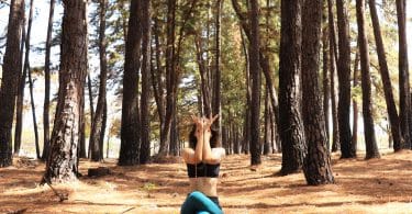 Mulher fazendo Yoga em uma floresta.