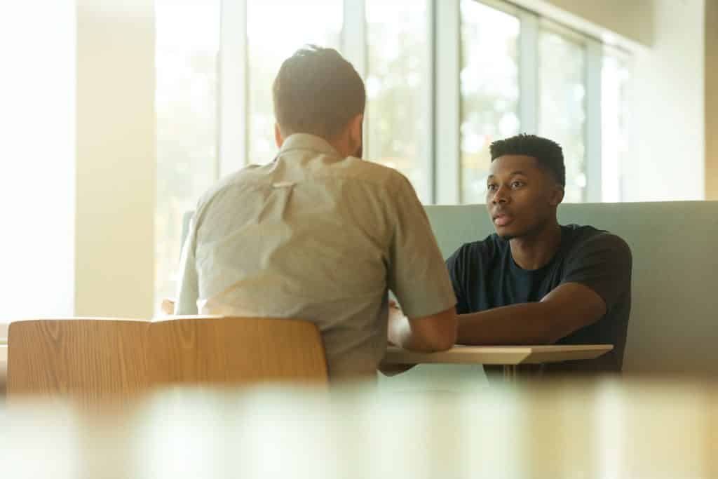 Homens branco e negro conversando.