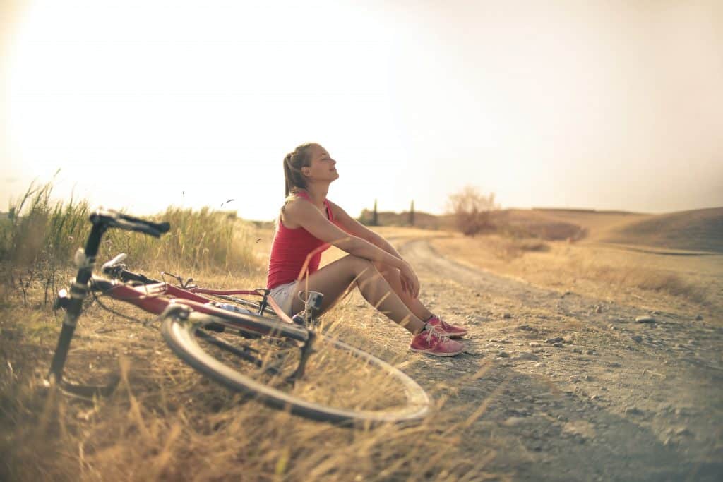 Mulher sentada em uma estrada depois de andar de bicicleta