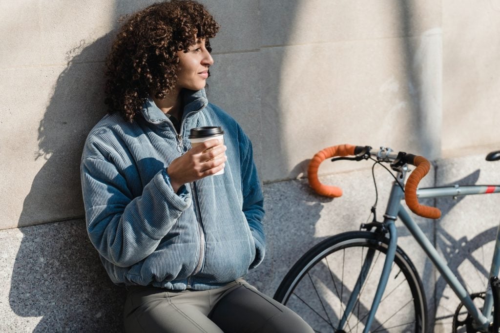 Mulher tomando café e observando a paisagem.